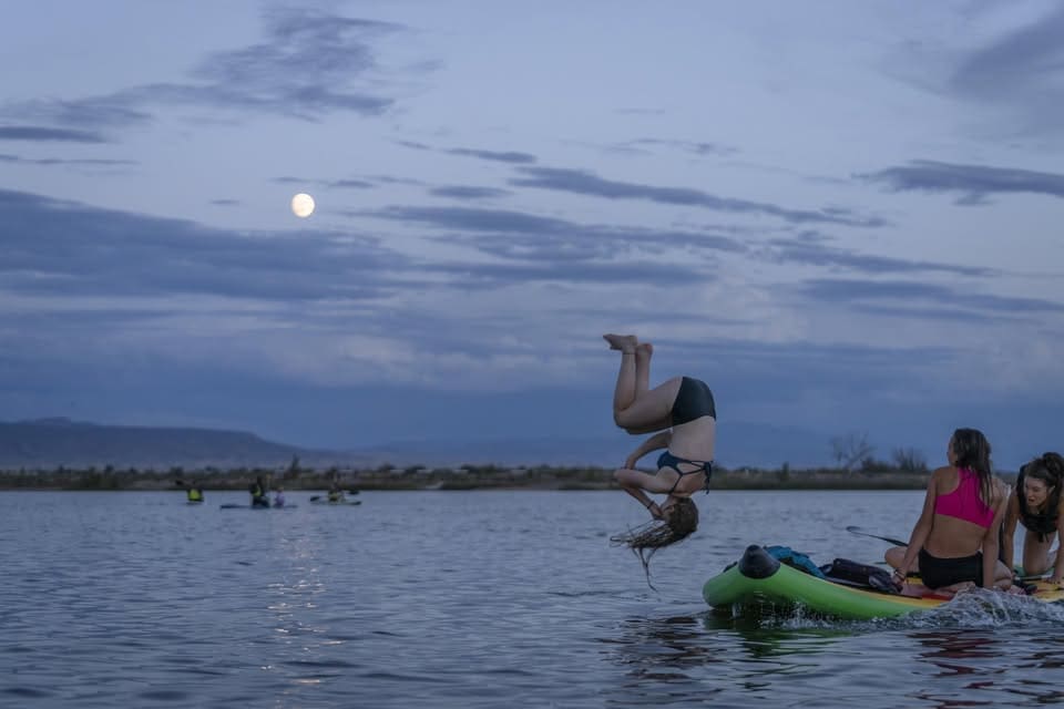 children jumping into a lake under a full moon